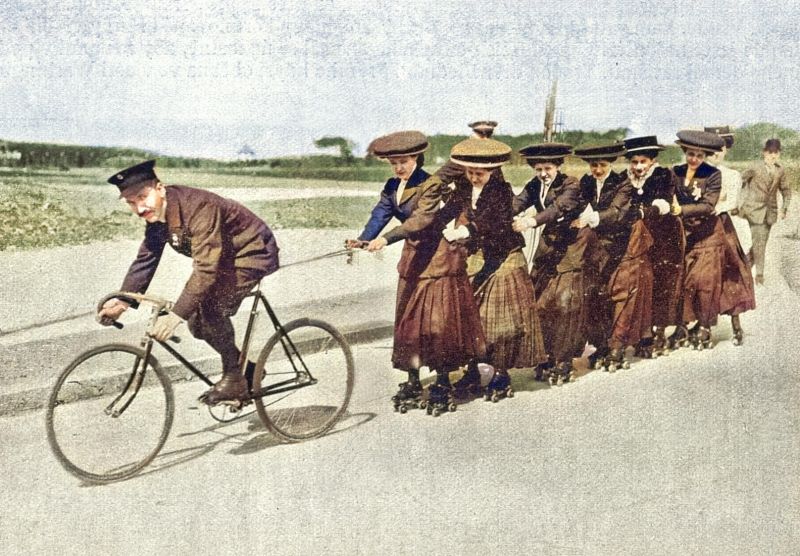 zobrazit detail historického snímku: Dámský průvod na kolečkách tažený velocipedem.