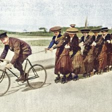 kolorovaná fotografie Dámský průvod na kolečkách tažený velocipedem.