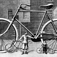 Obrovský bicykl reklamní. Před ním bicykl normální a dětský.